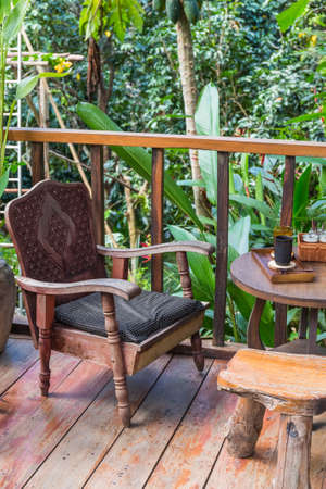 Relax corner beside the garden in Thai house with traditional wood chair and beverage on the tableの写真素材
