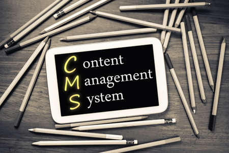 Content Management System (CMS) on mobile tablet with many pencils on the tableの写真素材