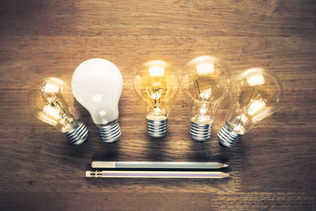 Glowing light bulbs with pencils on wood tableの写真素材