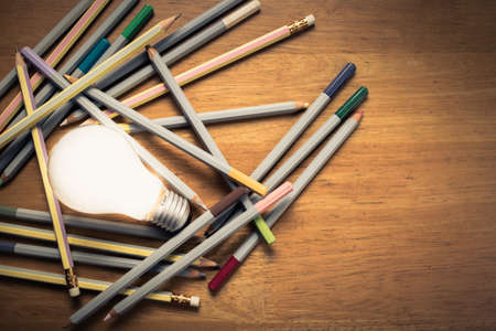 Glowing light bulb and pencils on the tableの写真素材