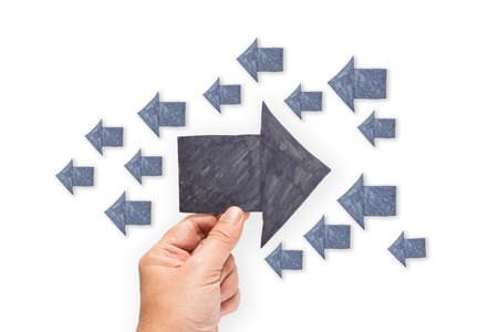 Hand hold a paper arrow to opposite direction from othersの写真素材