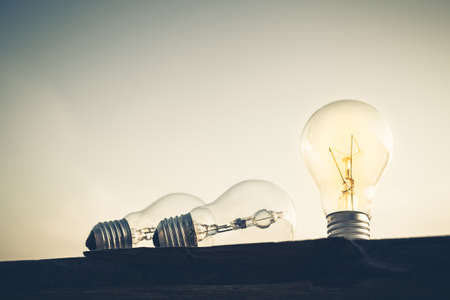 Standing light bulb glowing on silhouette plank, vintage color styleの写真素材