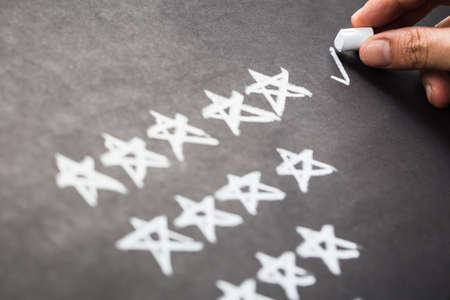 Closeup hand mark five stars rating on chalkboardの写真素材