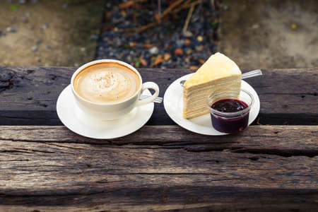 Cappuccino and blueberry crape cake on wood bench in the gardenの写真素材