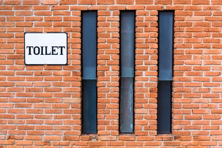 Brick wall with long windows and toilet sign, toilet exterior