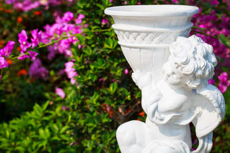Cupid statue in the garden with bougainvilleas flowerの写真素材