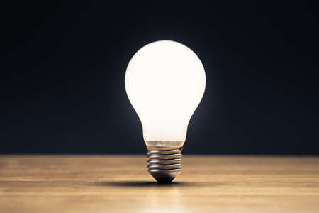 One white light bulb glowing on the tableの写真素材