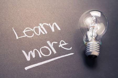 Handwriting of Learn More text with glowing light bulbの写真素材