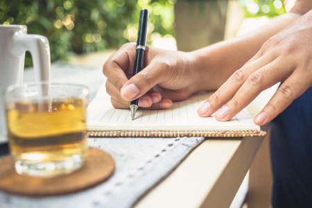 Writing outdoor in the garden with cup of teaの写真素材