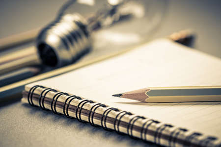 Creative writing, closeup pencil on notebook with light bulb on backgroundの写真素材