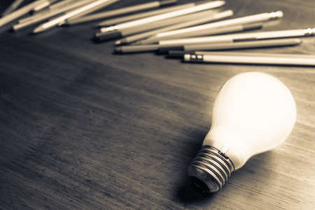 Creative Writing, glowing light bulb on the table with many pencilsの写真素材