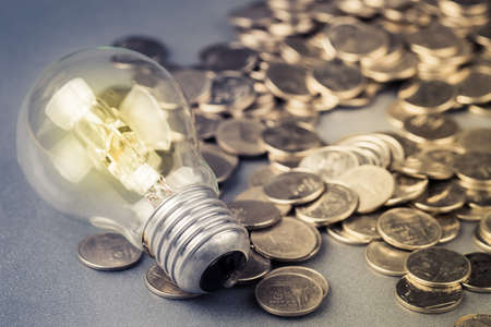 Glowing light bulb on many coinsの写真素材