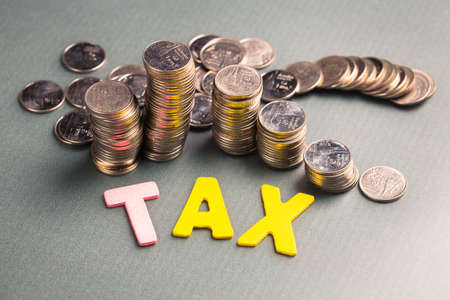 Closeup wood letters of Tax word with heap of coinsの写真素材