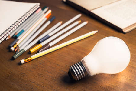 White light bulb glowing with many pencils as symbol of important equipment for writingの写真素材