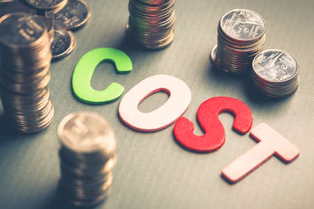 Closeup wood letters of Cost word with heap of coinsの写真素材