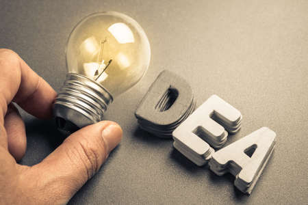 Hand place a glowing light bulb instead of letter for making idea happen conceptの写真素材