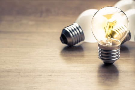 Small light bulb glowing on wood table