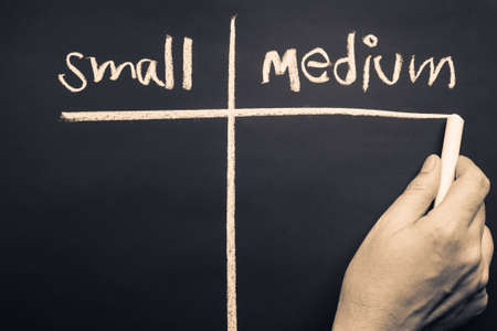 Hand writing divided chart of Small and Medium for comparison, SME or SMB concept