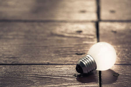 Small light bulb glowing on wood tableの写真素材