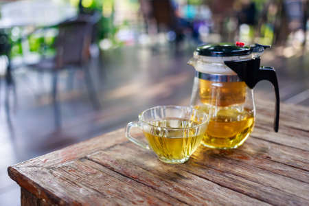 Cup of hot tea and teapot on wood table, shallow depth of field on blurred backgroundの写真素材