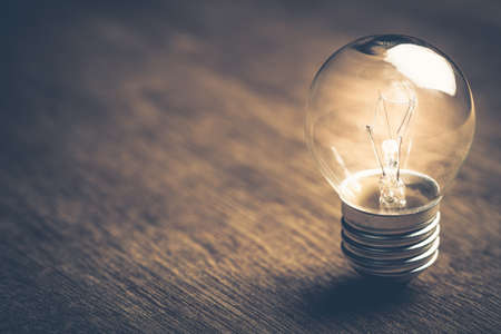 Small light bulb glowing on wood backgroundの写真素材