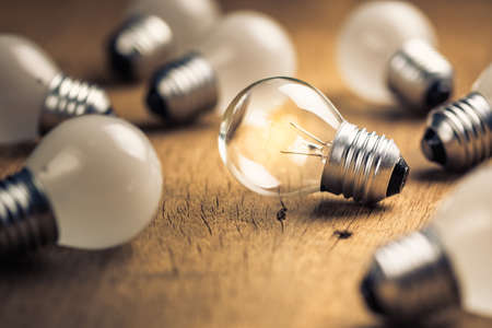 Transparent light bulb glowing among the white light bulbsの写真素材