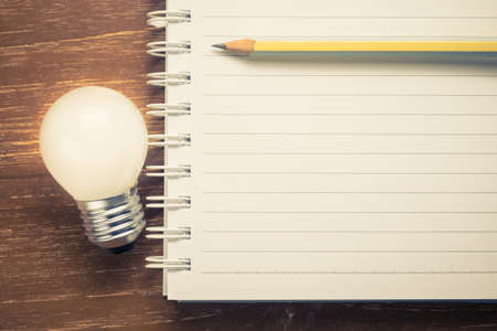 Closeup part of spiral notebook with glowing light bulb for inspire textの写真素材
