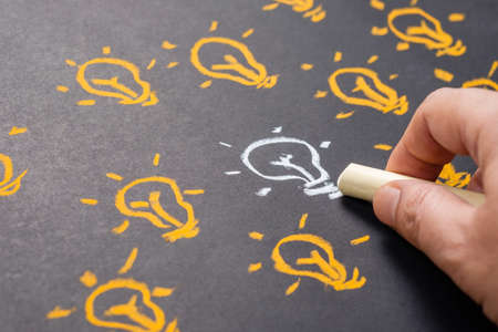 Similar but different, hand drawing white light bulb among the orange ones