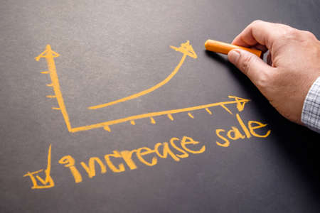 Closeup hand writing graph with text message Increase Sale on chalkboardの写真素材