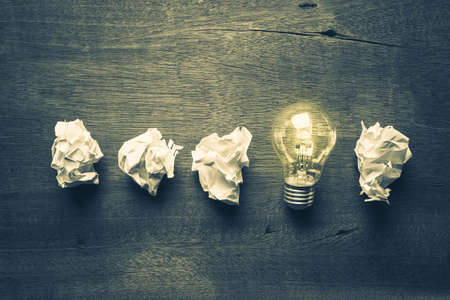 Light bulb glowing in a row of crumpled ball paperの写真素材