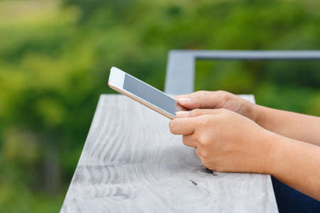 Closeup woman's hand use tablet outdoor with green forest on backgroundの写真素材