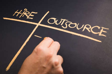 Hand write a chart of Hire and Outsource on chalkboard