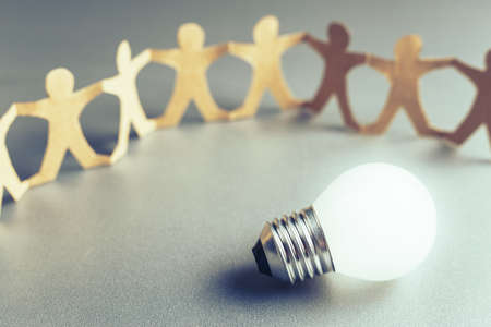 Glowing light bulb with human chain paperの写真素材