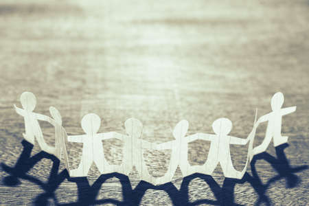 Human chain paper against the light on wood backgroundの写真素材