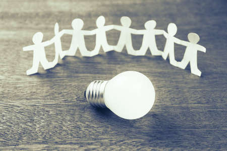 Glowing light bulb with human chain paperの写真素材