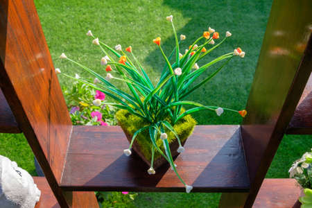 Artificial plant decorated on the wood shelf outdoor in the garden
