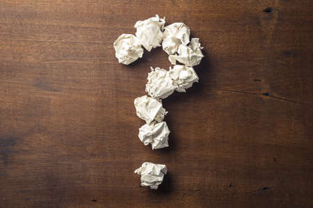 Question mark symbol arranged by crumpled ball paper on wood backgroundの写真素材