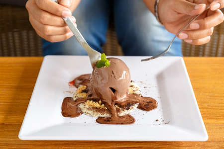 Closeup woman going to eat chocolate ice cream on white plateの写真素材