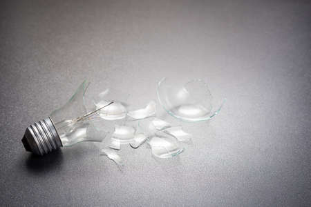 Broken light bulb on gray background with copy spaceの写真素材