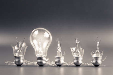 Perfect light bulb glowing in a row of broken bulb for solution conceptの写真素材