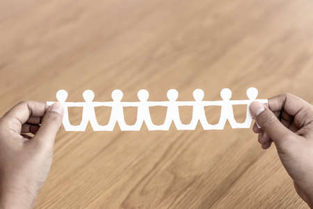 Hand show a paper human chain on wood background