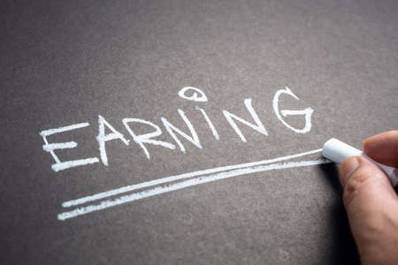 Closeup hand write a word EARNING on chalkboardの写真素材