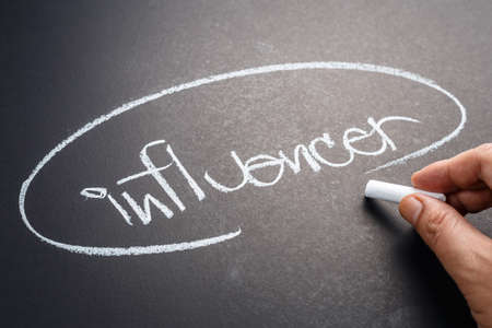 Closeup hand write a topic INFLUENCER on chalkboardの写真素材