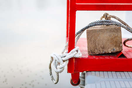 Square stone anchor and old rope on the pontoonの写真素材
