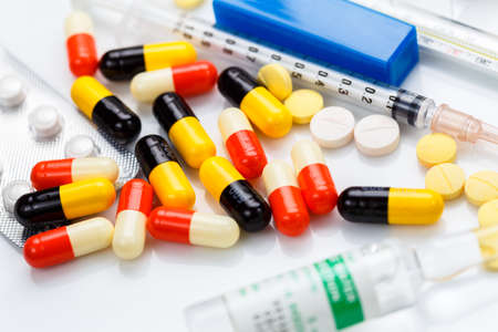 Closeup medicine capsule and tablet with part of syringe and vialsの写真素材