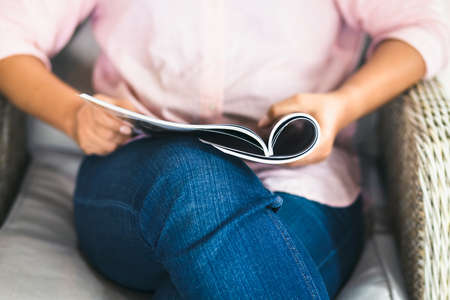 Closeup woman sit in armchair and read the magazine on her lapの写真素材