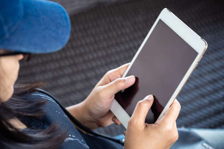 Closeup asian woman in casual cloths sitting on weaved chair and read the tablet