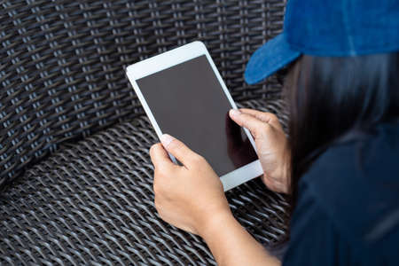 Closeup woman lie down on the weaved chair and read tablet