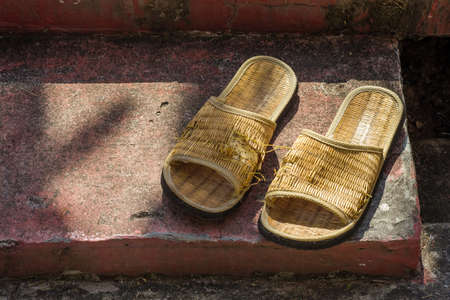 Pair of handmade woven flipflop on the floor is torn and partly damageの写真素材