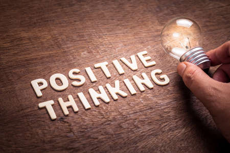 Positive Thinking text by wood letters with glowing light bulbの写真素材